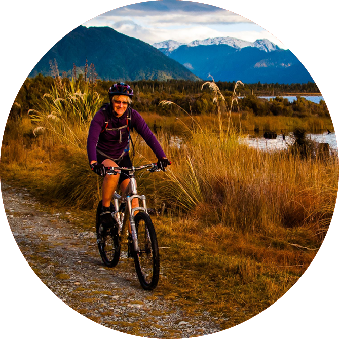 A woman smiling riding her bike through beautiful landscape